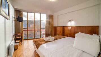Een hotelkamer met een groot bed, een bureau en een raam met uitzicht op de stad.