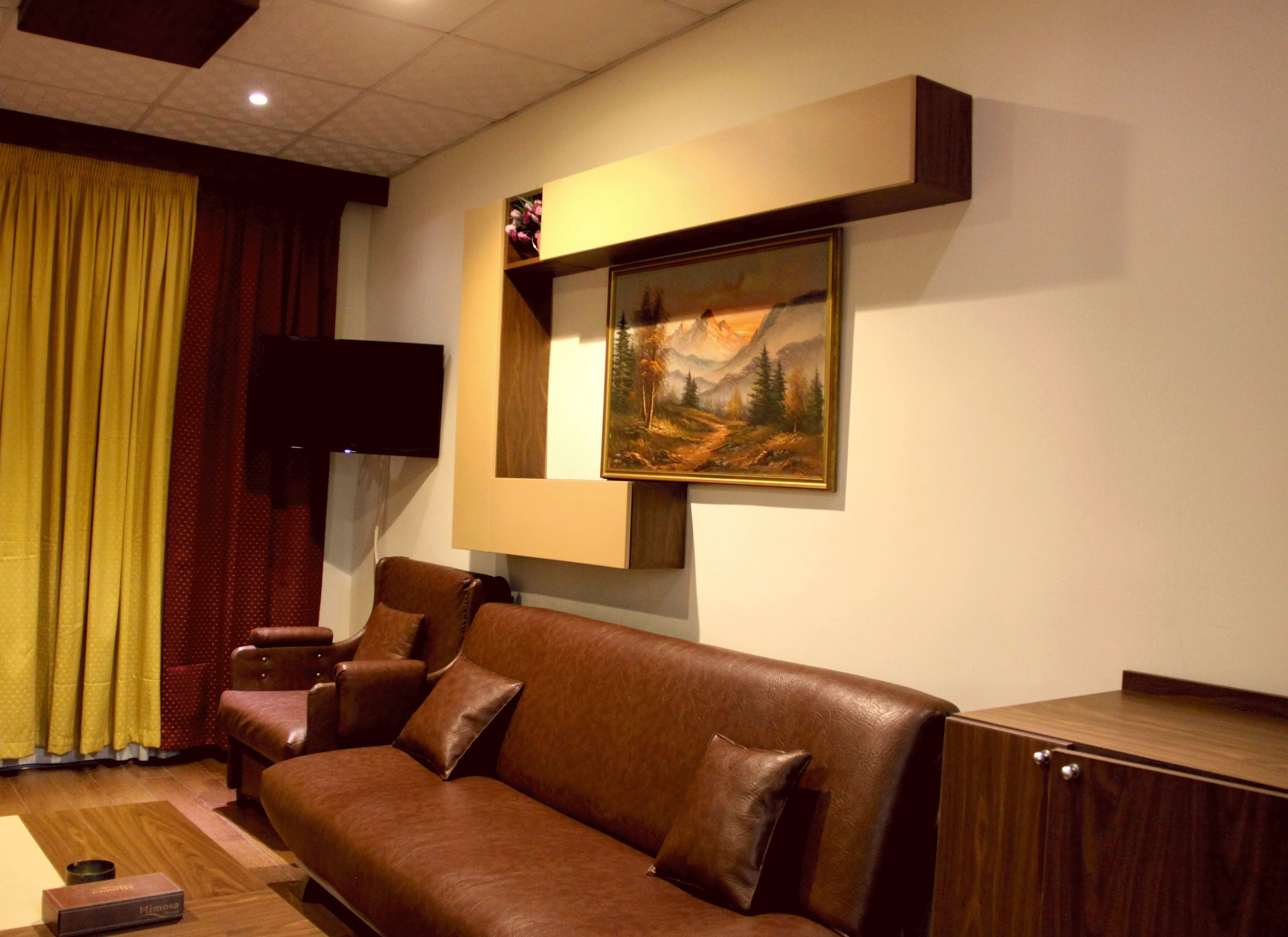 Una sala de estar moderna con un sofá de cuero marrón, un cuadro colgado y un televisor de pantalla plana.