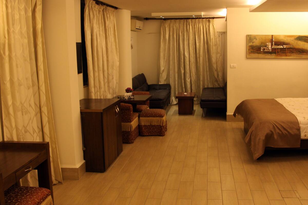 Habitación de hotel con cama, escritorio, silla, sofá y una mesita.