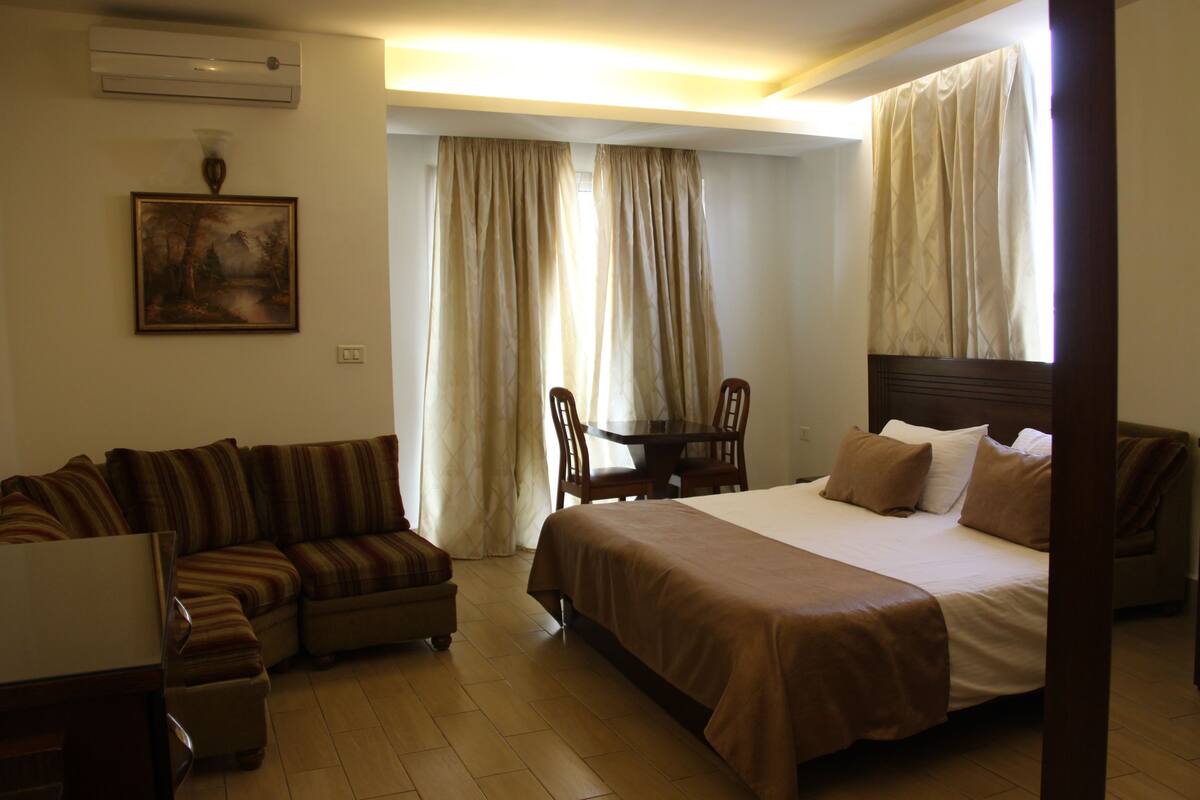 Una habitación de hotel con una cama grande, un sofá, una mesita y una silla.