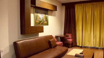 A living room with a brown leather sofa, a small round table, and a painting on the wall.
