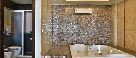 Un baño con pared de mosaicos, una bañera y un inodoro.