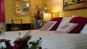 Ein Zimmer aus Holz mit einem Bett, einem Spiegel, einer Vase mit Blumen und einem Bild an der Wand.