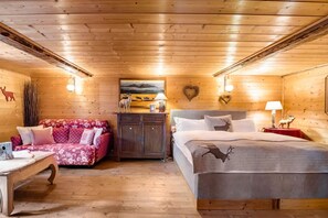 A cozy log cabin room with a bed, a sofa, and a small table. - CHALET DEI FIORI - ROOM & APARTMENT (Bedretto)