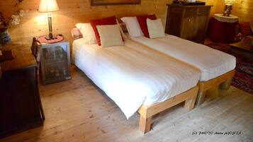 A wooden room with a bed, two bedside tables, a dresser, and a painting on the wall.