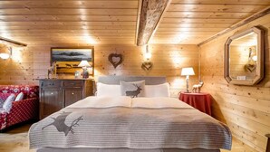 Een gezellig houten slaapkamer met een bed, een dressoir, een nachtkastje en een rode bank.
