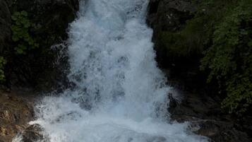 A waterfall cascading over dark rocks with lush greenery around.
