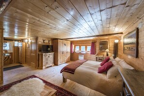 A wooden cabin interior with a bed, a television, and a dining area. - CHALET DEI FIORI - ROOM & APARTMENT (Bedretto)