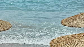 A beach scene with thatched umbrellas and the ocean waves. - Atlantica Grand Mediterraneo Resort - Adults Only (Corfu)