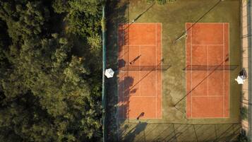 An aerial view of a tennis court surrounded by dense trees.