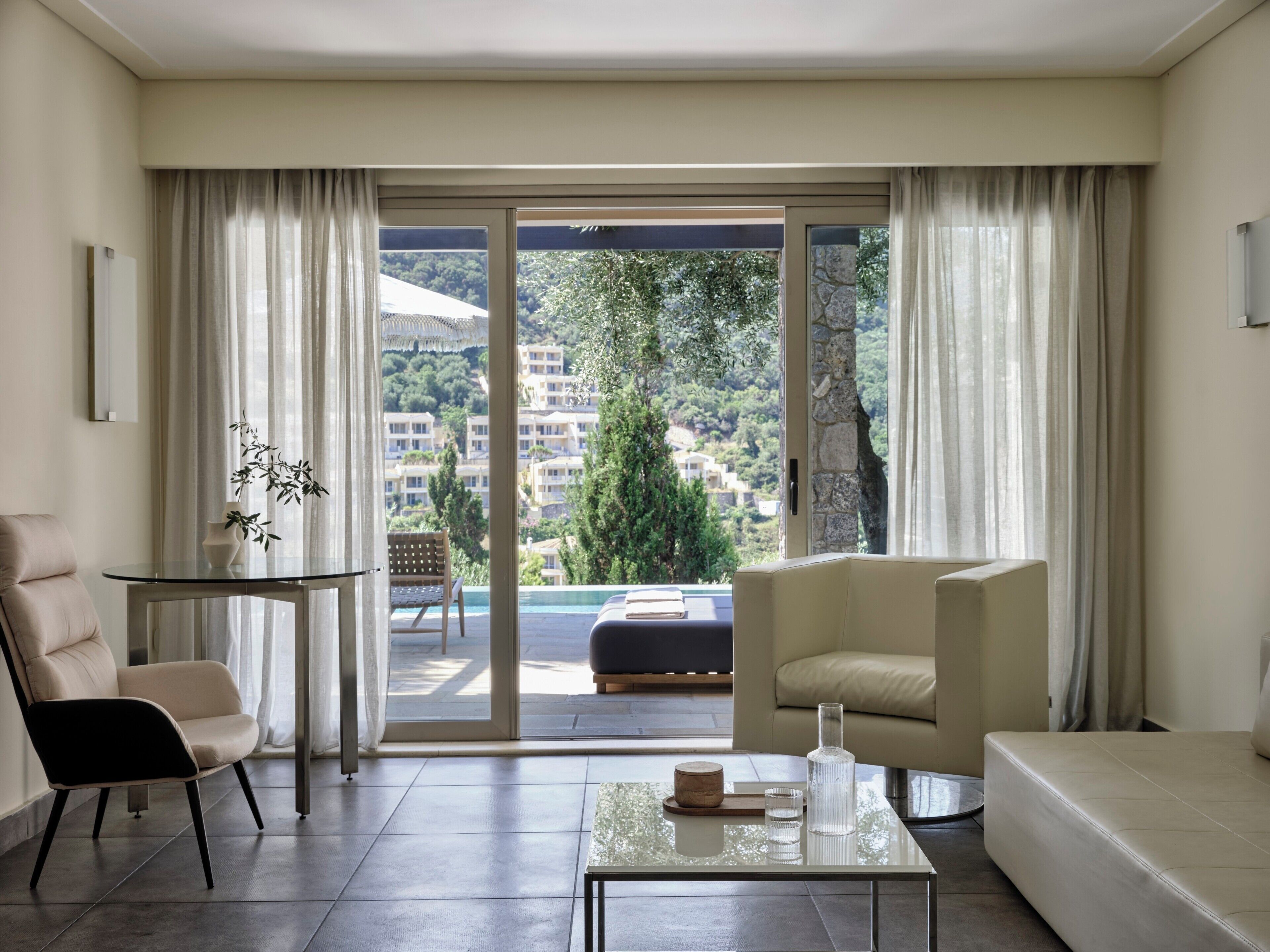Un salon moderne avec un canapé, un fauteuil et une table basse en verre.