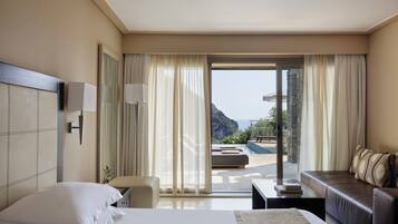 Habitación de hotel con cama, sofá, escritorio y vista al mar.
