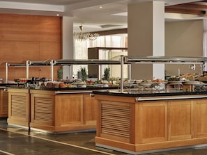 A buffet area with wooden cabinets and a variety of food items. - Atlantica Grand Mediterraneo Resort - Adults Only (Corfu)