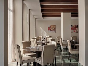 A modern dining area with high ceilings and natural light, featuring tables and chairs arranged for guests. - Atlantica Grand Mediterraneo Resort - Adults Only (Corfu)