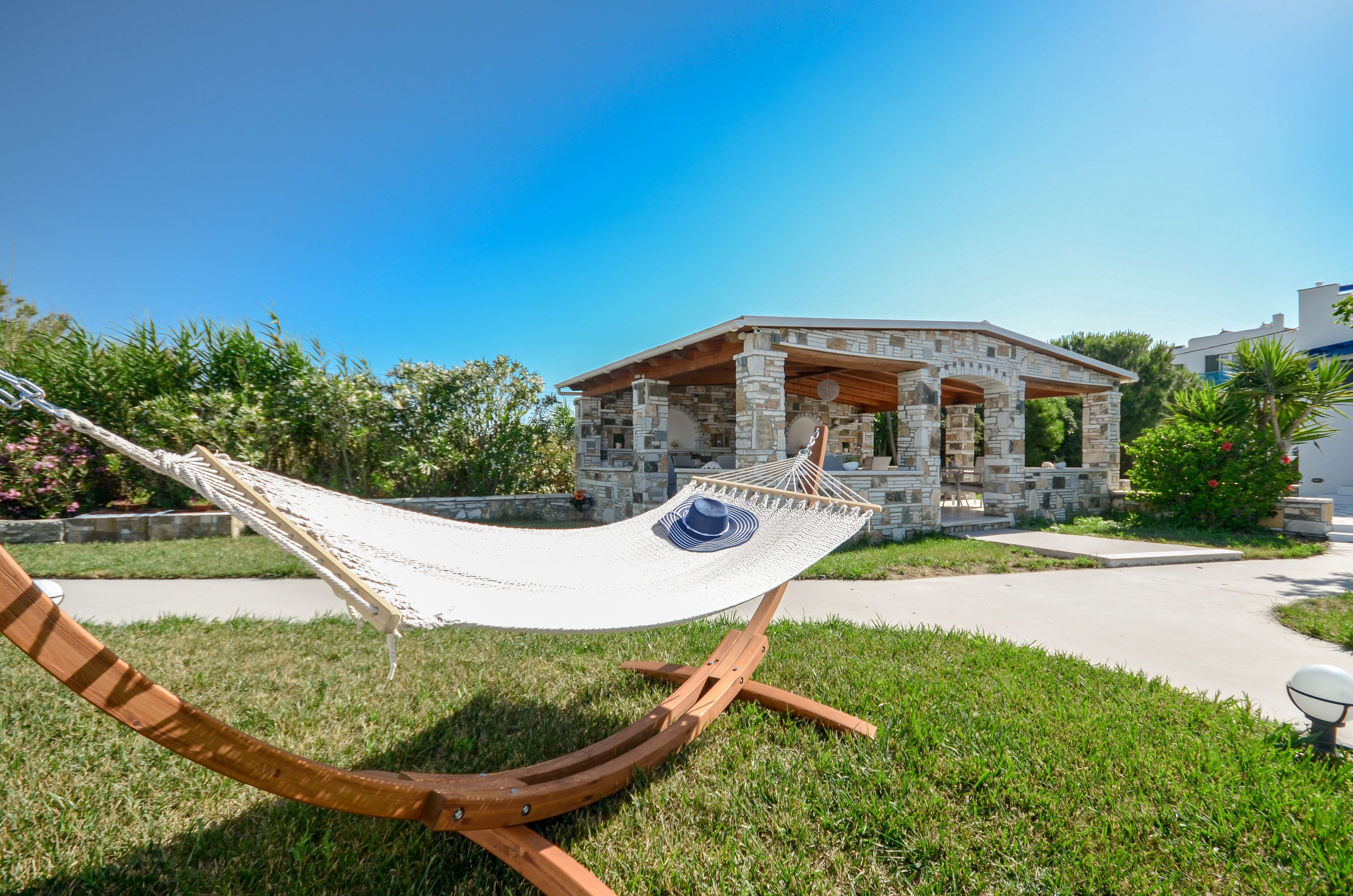 A hammock in a grassy area with a stone building in the background.