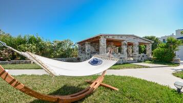 A hammock in a grassy area with a stone building in the background.