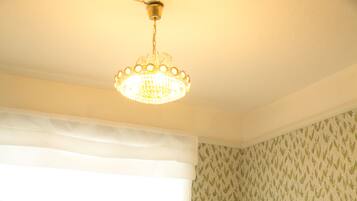 A room with a white sofa, a small round table with a vase and cups, a radiator, and a patterned wallpaper.