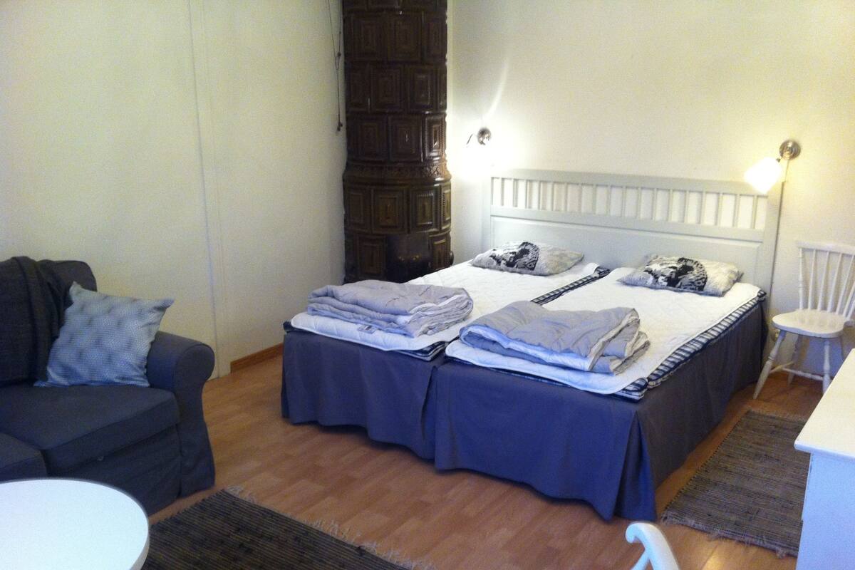 Quarto de hotel com cama, uma cadeira, uma mesinha e um sofá.