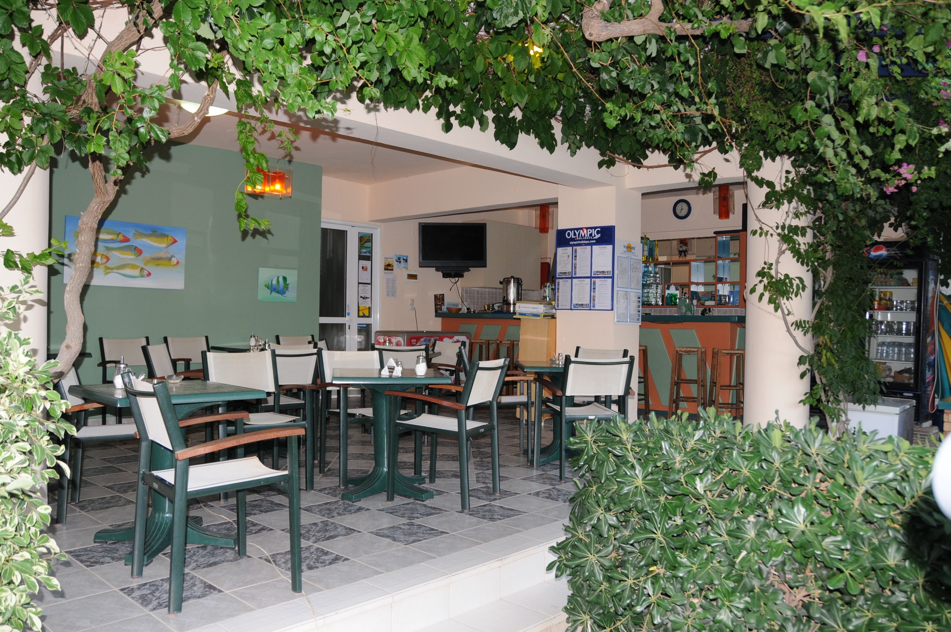 A restaurant with outdoor seating, a kitchen area, and a wall with a poster.