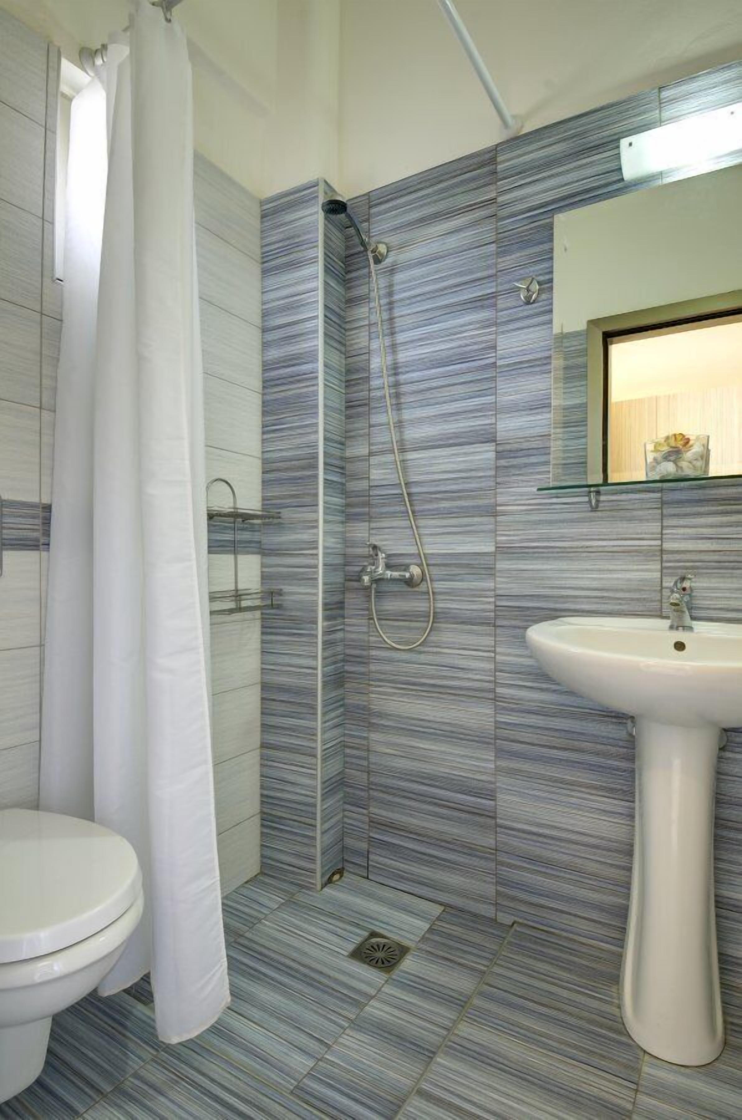 A bathroom with a shower, toilet, and sink.