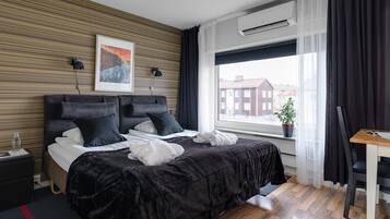 Een moderne hotelkamer met een groot bed, een bureau en een raam met uitzicht op de stad.
