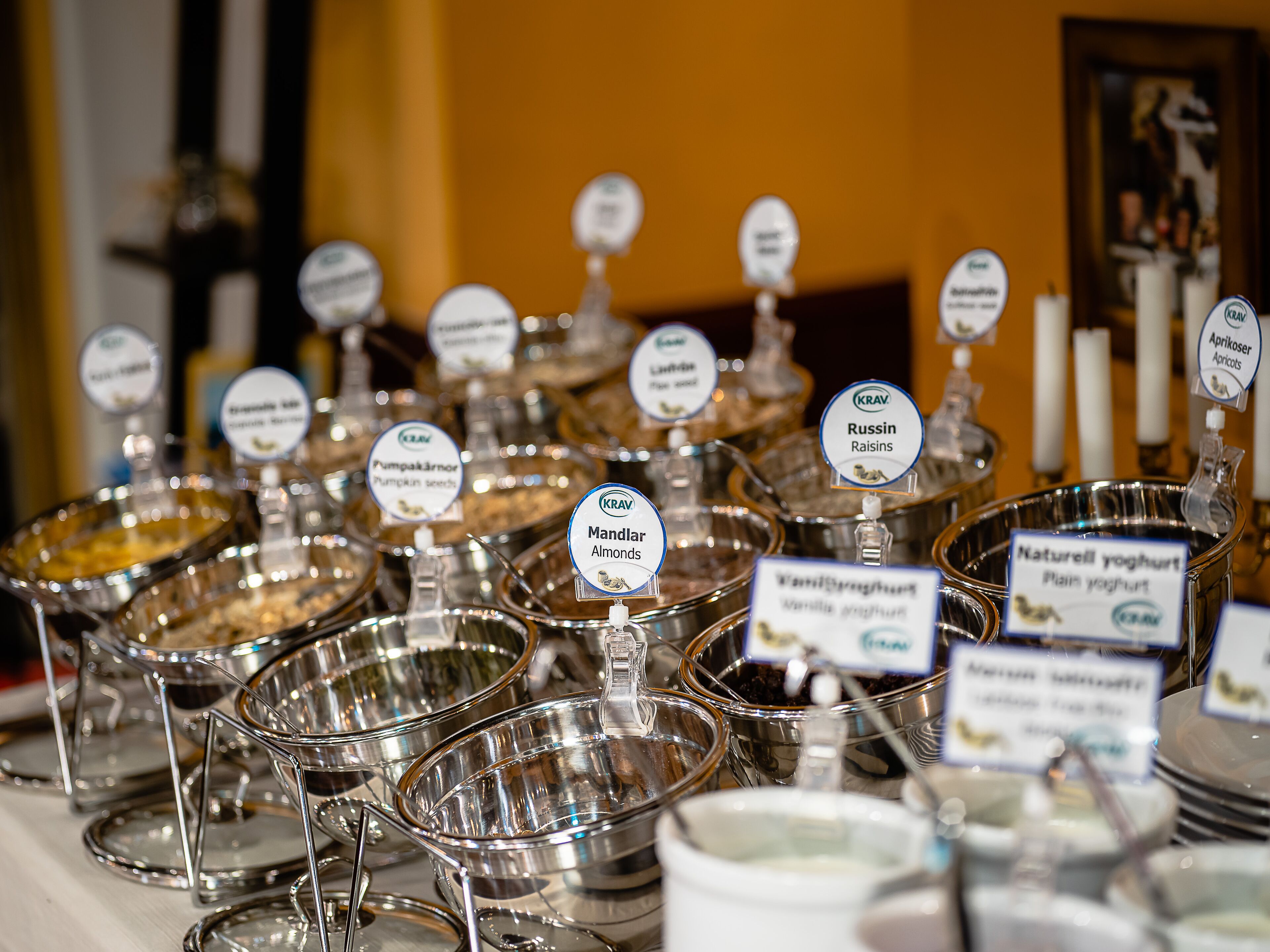 A buffet with various labeled dishes including pumpkin seeds, almonds, and natural yogurt.