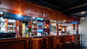 A bar area with wooden paneling, a reception desk, and bar stools. - Wärdshuset C. Dickens (Fagersta)