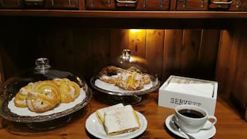 Un bufé de desayuno con pastelería, una taza de café y un letrero que dice "SERVETT".