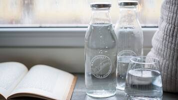 Two glass bottles and a glass on a windowsill with an open book.