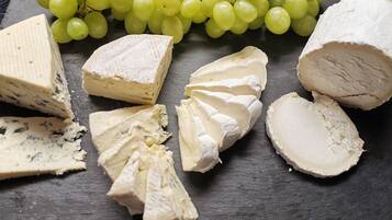 A selection of cheeses and grapes on a slate board.