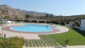 Una piscina con un deck circundante, una zona de estar y vistas a un paisaje montañoso.