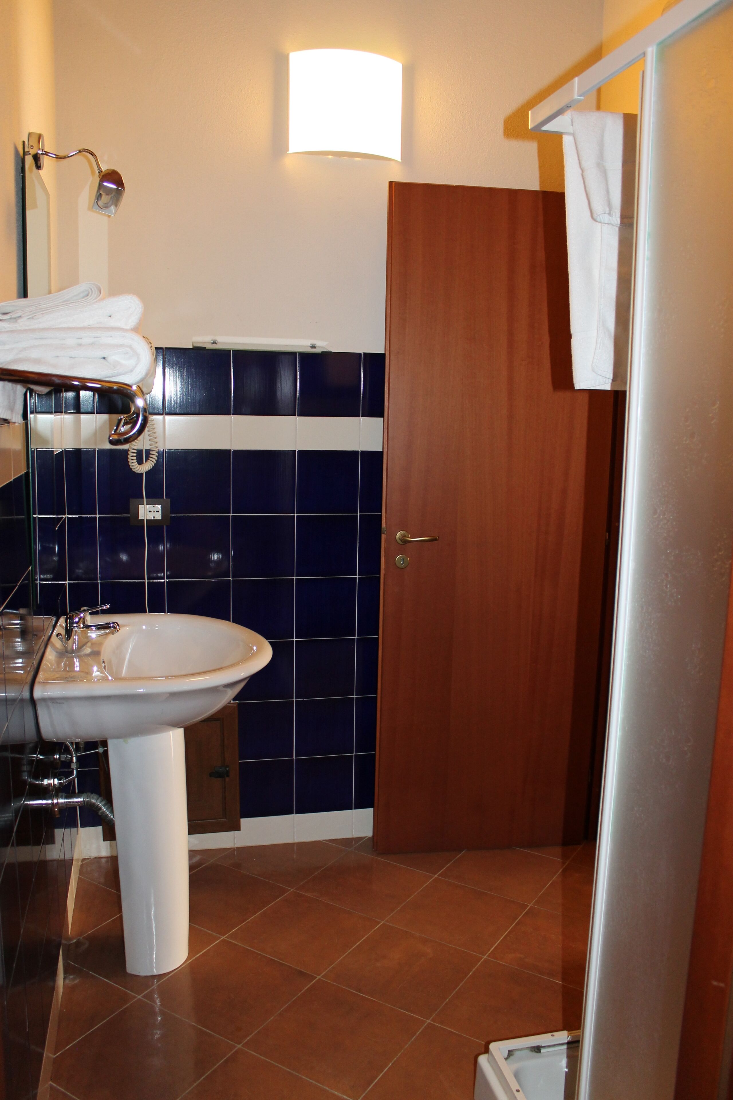 Un baño con lavamanos, espejo, toallero y puerta.