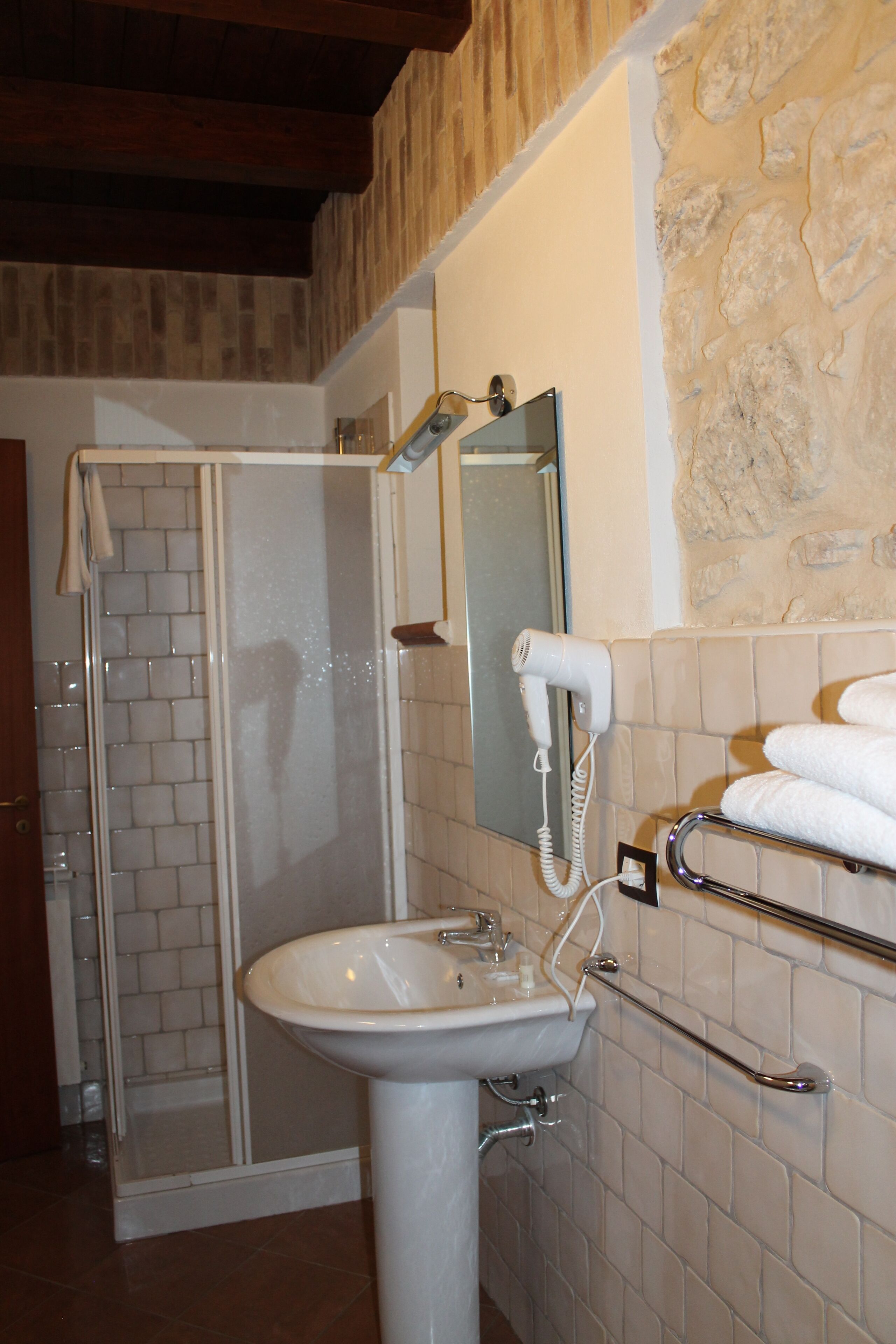 Une salle de bain avec une douche à parois de verre, un lavabo, un porte-serviettes et un miroir.