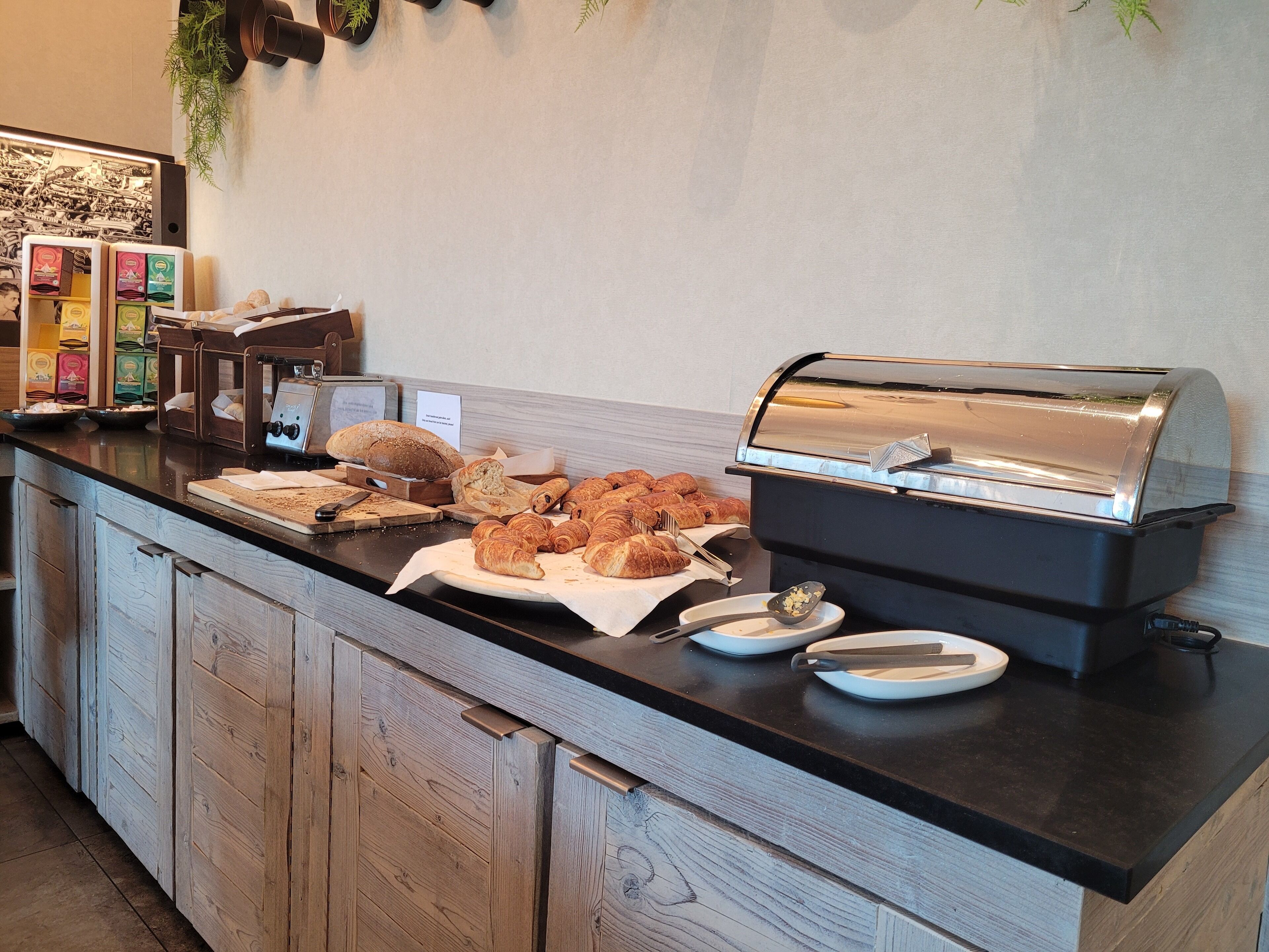 A buffet counter with various baked goods, a toaster, and a coffee machine.