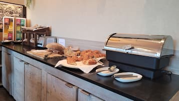 A buffet counter with various baked goods, a toaster, and a coffee machine.