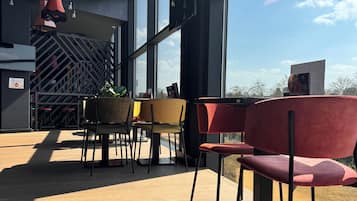 Ein modernes Interieur mit großen Fenstern, roten Stühlen und Holzboden.