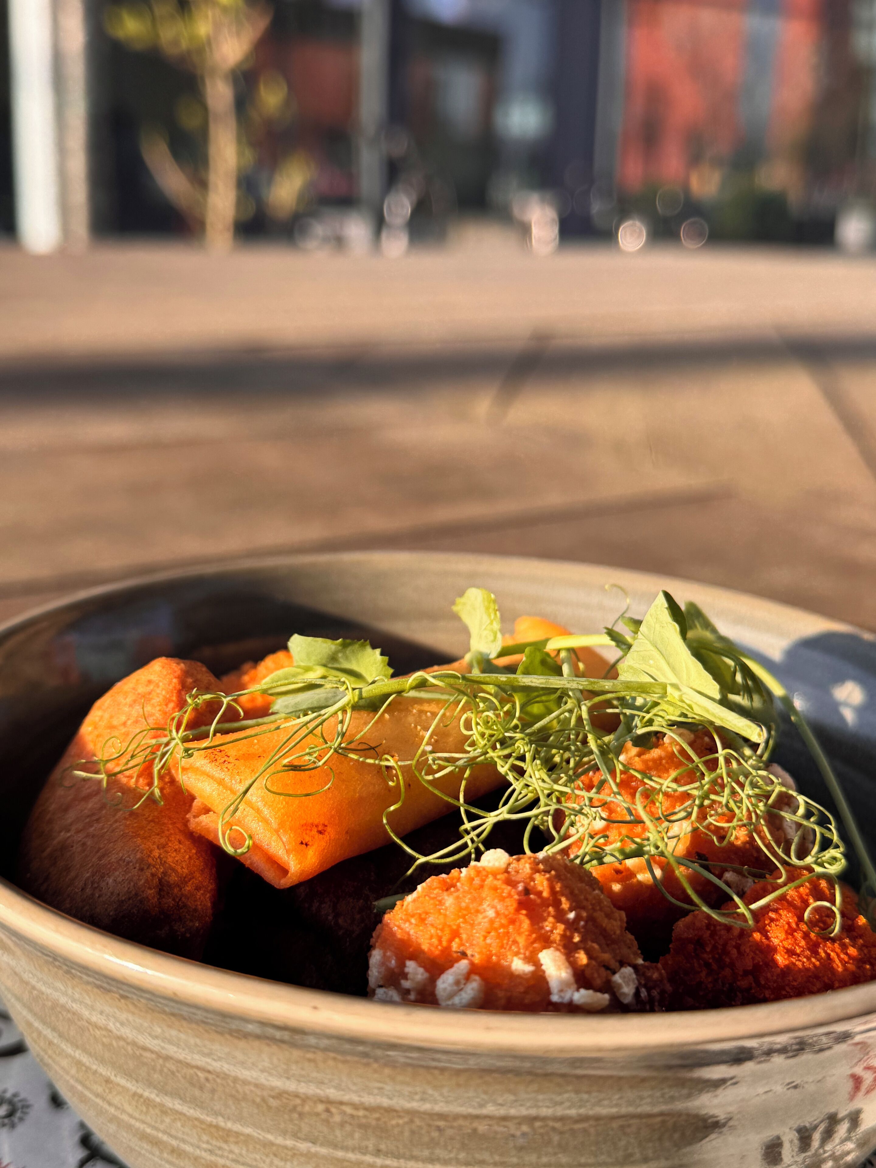 A bowl of food with various ingredients, including greens and possibly some meat, served in a ceramic bowl.