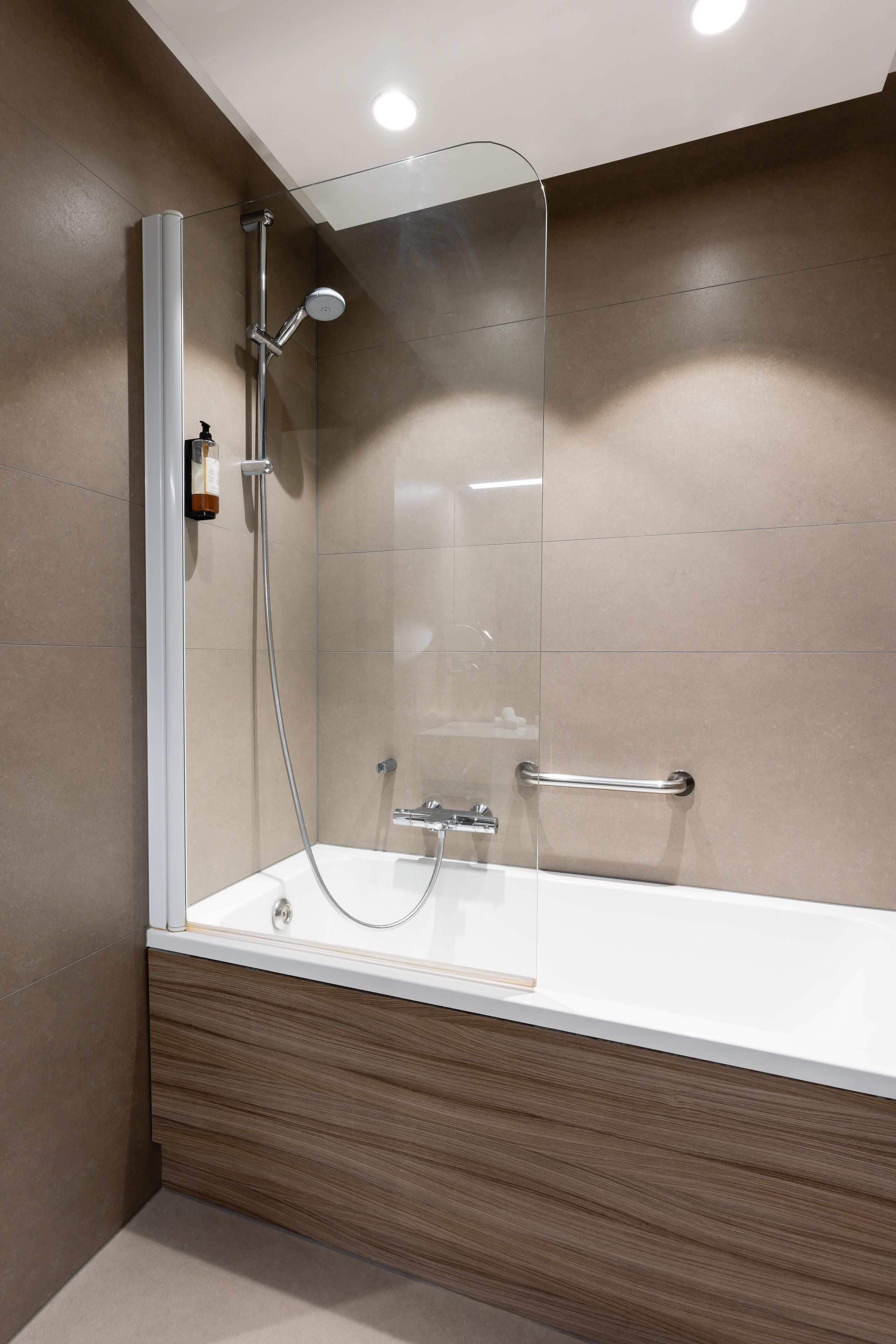 Une salle de bain moderne avec une douche à parois de verre, une baignoire blanche et un meuble-lavabo en bois.