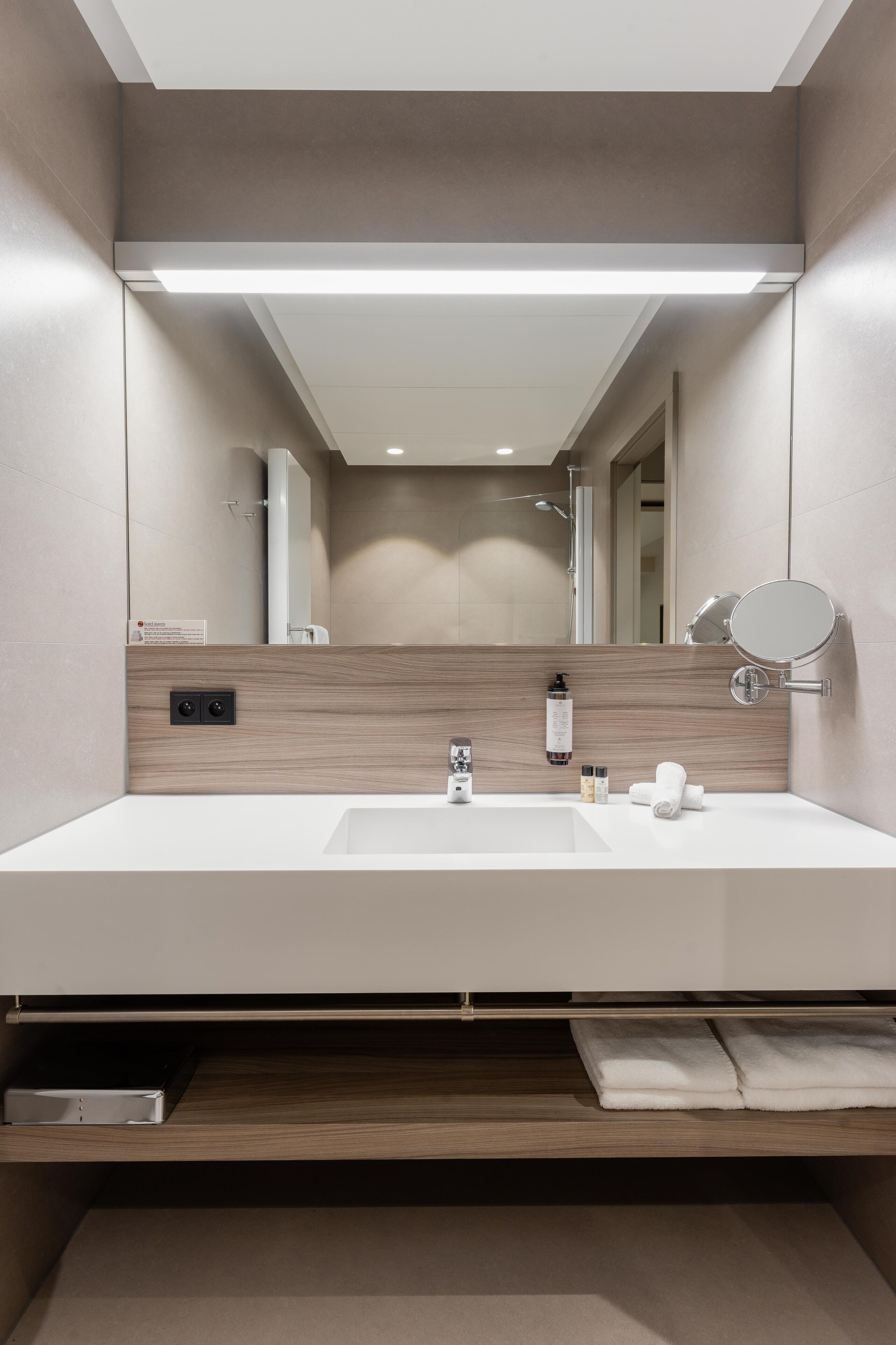 Een moderne badkamer met een grote spiegel, een wastafel en een douchehoek.