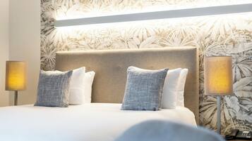 A hotel room with a large bed, two bedside lamps, and a floral wallpaper.