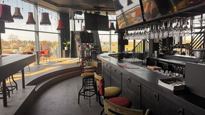 A modern bar area with a curved counter, stools, and a large window offering a view of the outside.