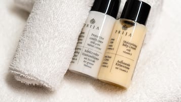 A white towel and two bottles of PRITA body cream on a white surface.