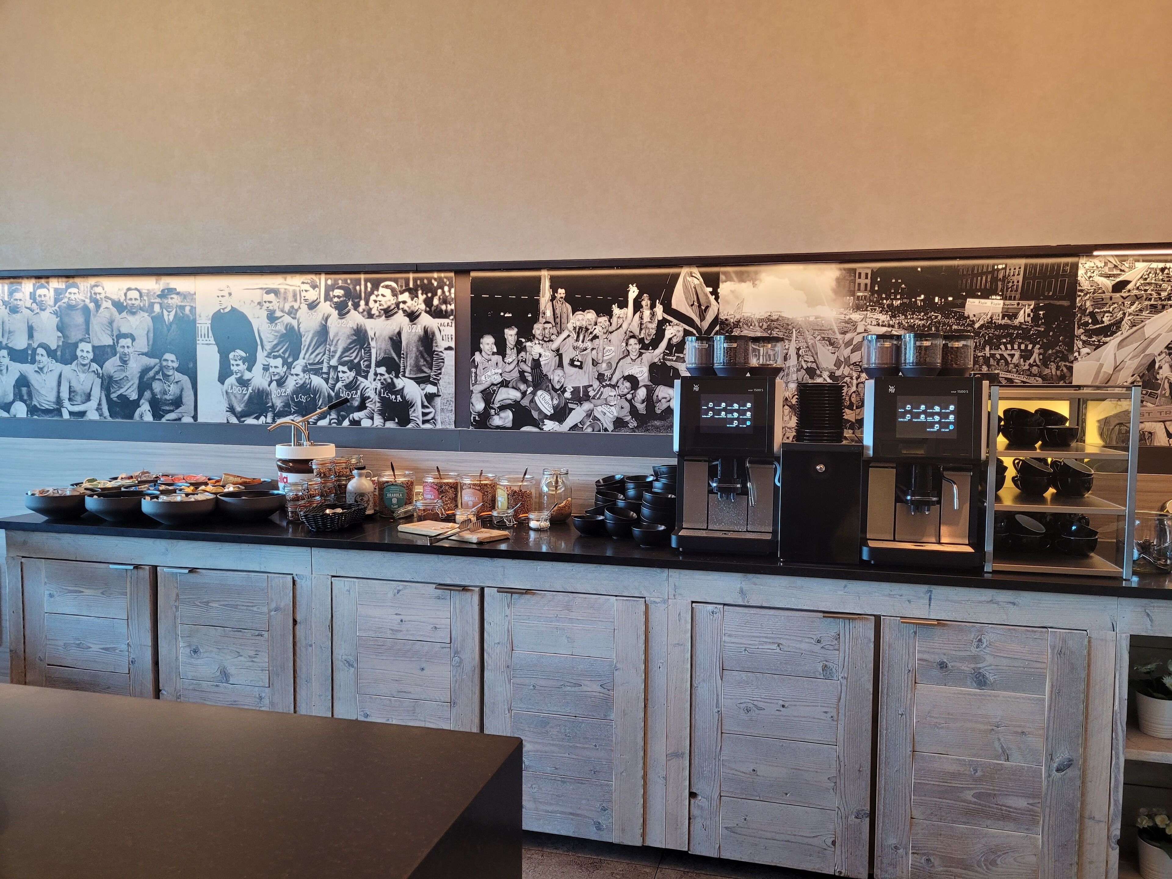 A bar area with a coffee machine, condiment dispensers, and a display of mugs and bowls.