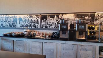 A bar area with a coffee machine, condiment dispensers, and a display of mugs and bowls.