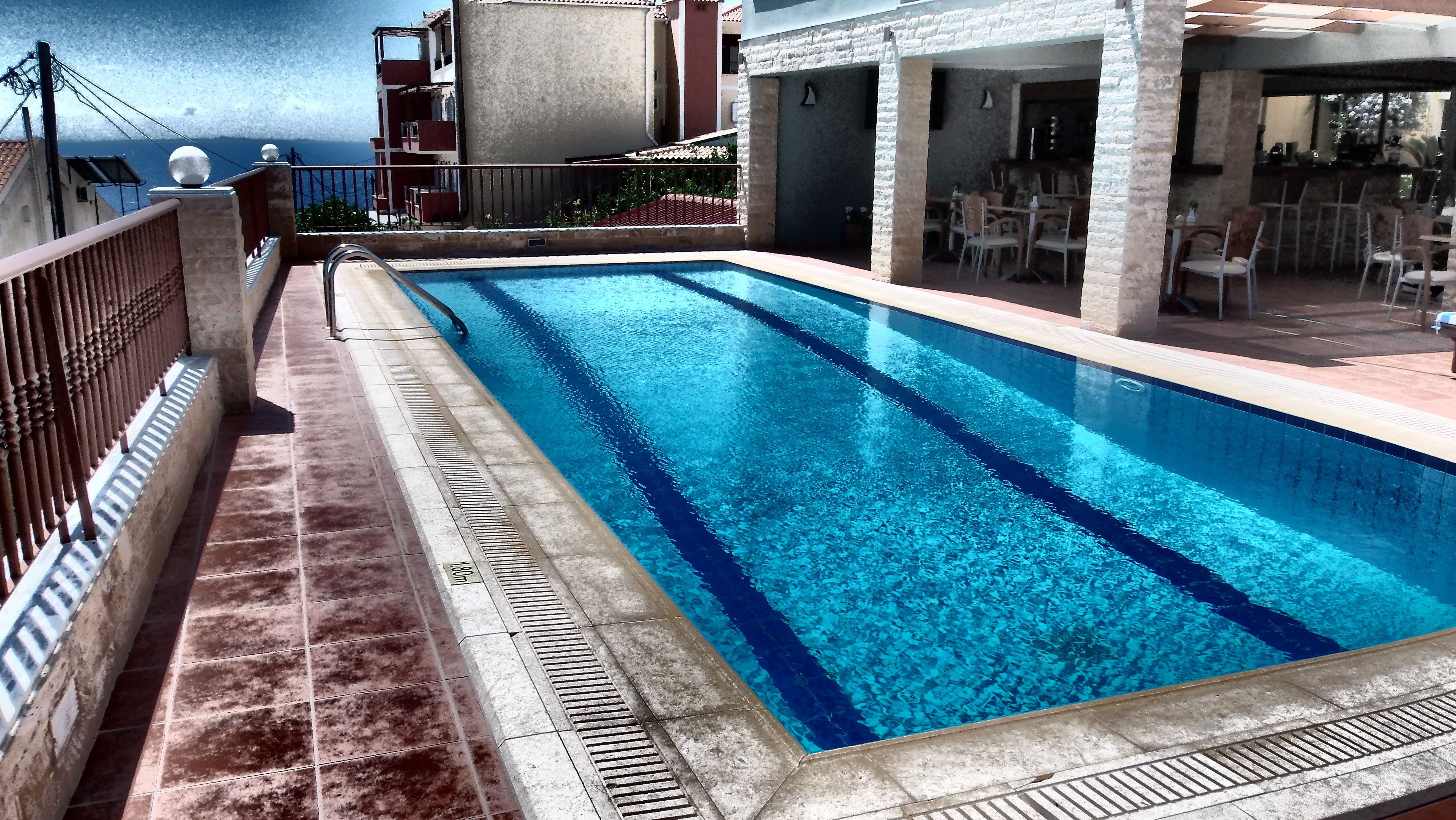 A rectangular swimming pool with clear blue water, surrounded by a tiled deck.