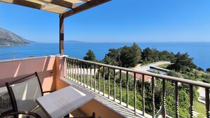 A balcony with a view of the sea, a table, and chairs. - Anastazia Hotel (Kefalonia)