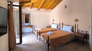 A bedroom with two beds, a mirror, a bedside table, a lamp, and a window with curtains. - Anastazia Hotel (Kefalonia)