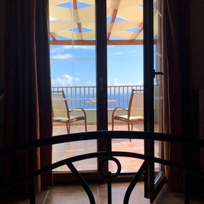 A balcony with a view of the sea, a chair, and a table.
