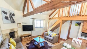 A cozy living room with a fireplace, a sofa set, a coffee table, and a staircase. - Beeches Farmhouse Country Cottages & Rooms (Bradford-on-Avon)
