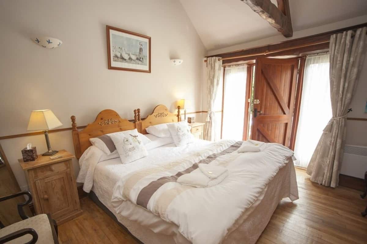 Une chambre à coucher avec un lit en bois, des tables de chevet, une chaise et une fenêtre avec des rideaux.